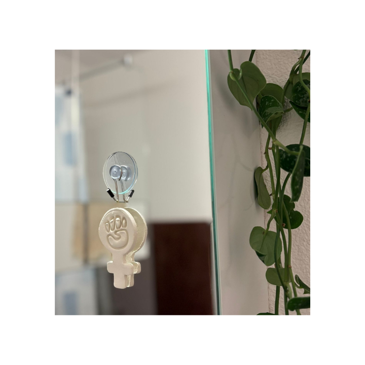 Handgefertigtes feministisches 3D-Wandbild aus Modelliermasse, aufgehängt im Wohnraum mit transparenter Wandhalterung