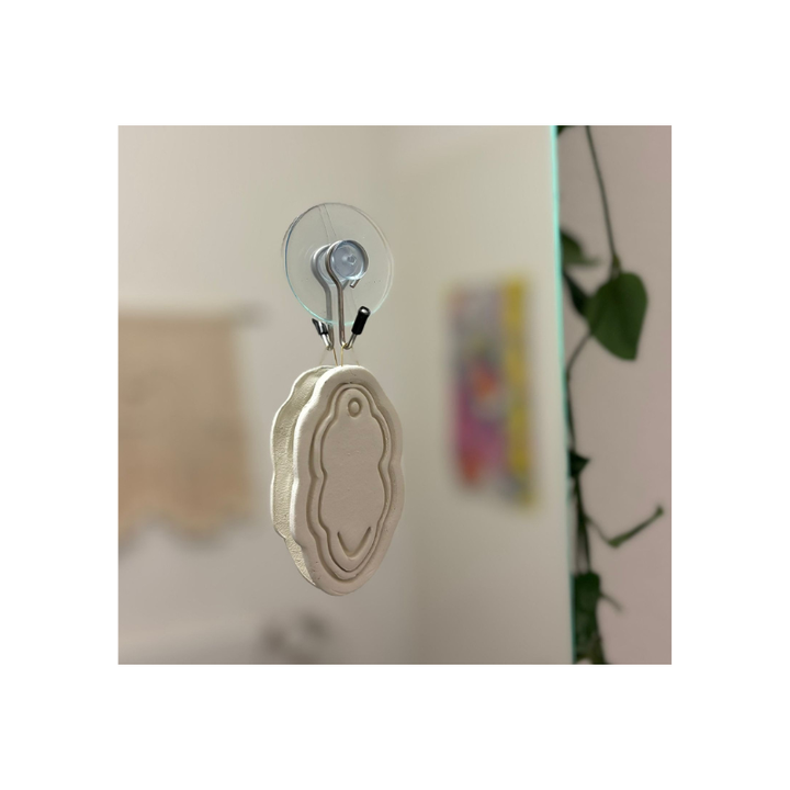 Handgefertigtes feministisches 3D-Wandbild mit Vulva-Motiv aus Modelliermasse, aufgehängt mit transparenter Wandhalterung