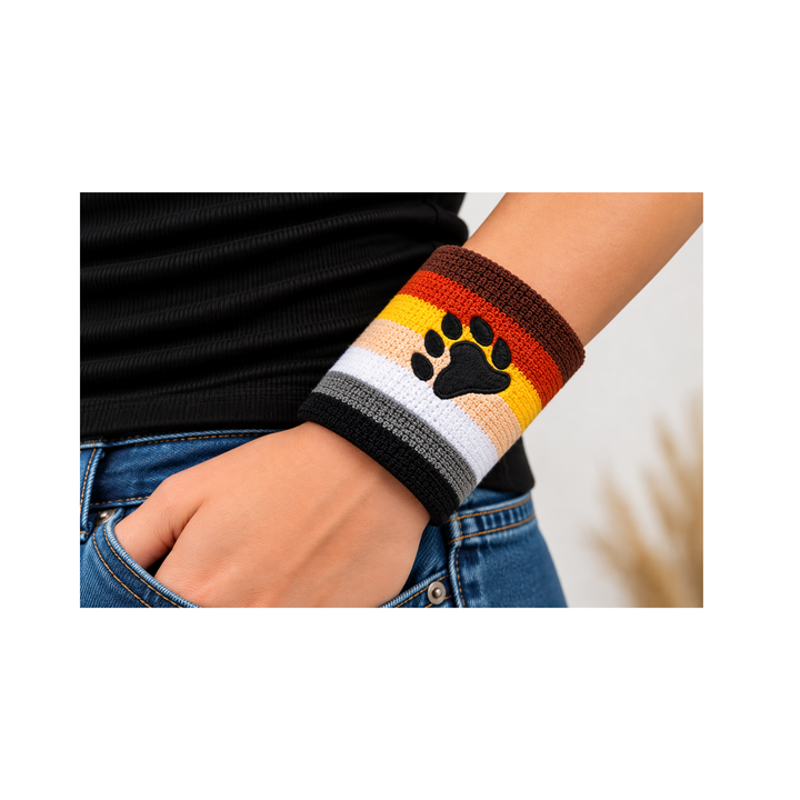 Bear Pride Schweissband mit gestickter schwarzer Bärentatze und Regenbogenstreifen der Bear Pride Flagge, getragen am Handgelenk zu Jeans