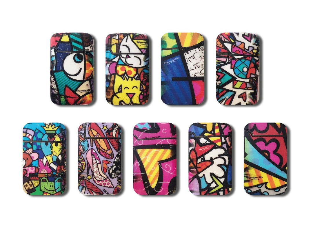 Jet-Flame-Feuerzeugen der Marke BRITTO, gestaltet im ikonischen Pop-Art-Stil von Romero Britto. Die Feuerzeuge zeigen lebendige Muster mit kräftigen Farben, abstrakten Formen und Motiven wie Herzen, Augen und Schmetterlingen. Die gelbe Verpackung ist ebenfalls mit kleinen Schmetterlingen verziert und trägt die Aufschrift „Jet Flame – High Quality – Refillable Lighter“ sowie „Easy Torch“ für einfache Handhabung.