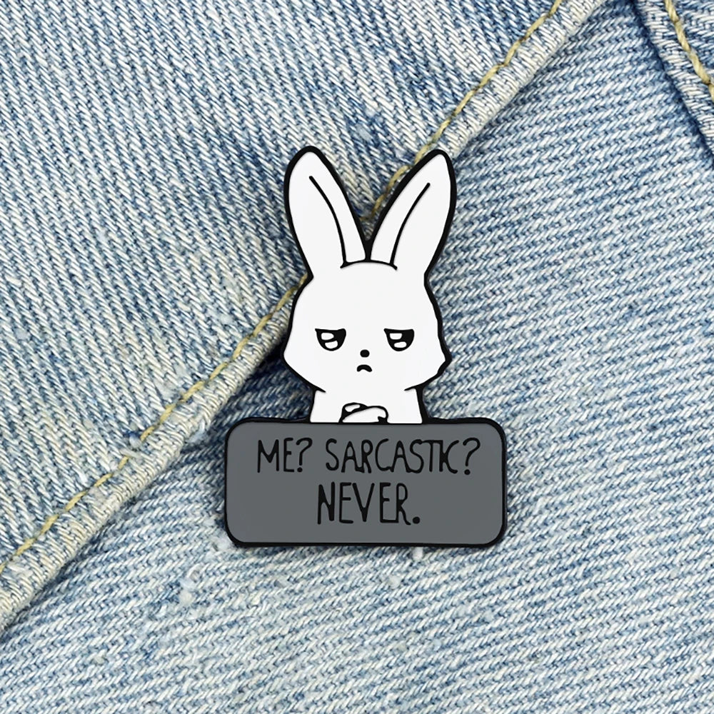 Emaille-Pin mit weißem Hasen und Aufschrift „ME? SARCASTIC? NEVER“ an einer Jeansjacke befestigt