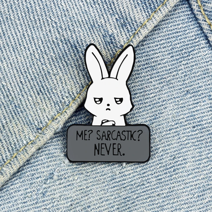Emaille-Pin mit weißem Hasen und Aufschrift „ME? SARCASTIC? NEVER“ an einer Jeansjacke befestigt