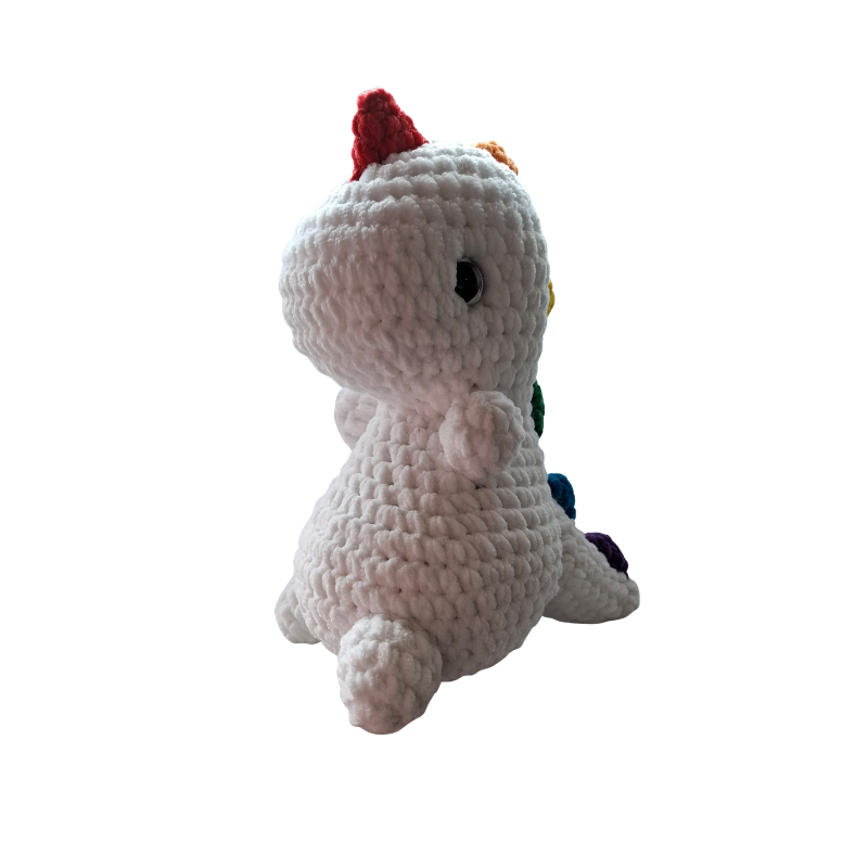 Gehäkelter Regenbogen Dino Pride Kuscheltier Handmade aus der Schweiz Seitenansicht mit bunten Pride Spikes und weißem Körper