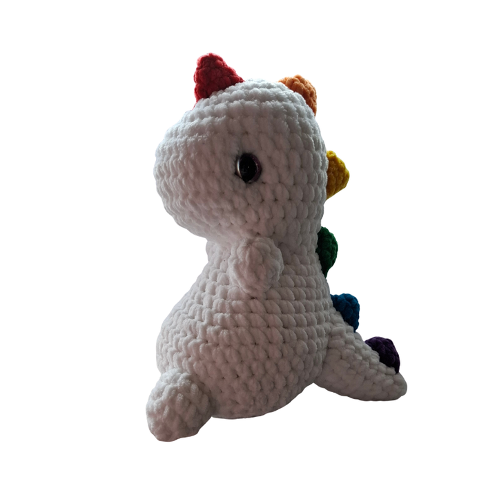 Gehäkelter Regenbogen Dino Pride Kuscheltier Handmade aus der Schweiz Seitenansicht mit bunten Pride Spikes und weißem Körper