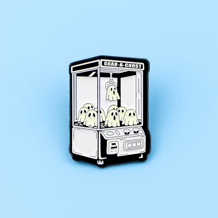 Cartoon-Pin einer Krallenmaschine mit kleinen Geistern auf hellblauem Hintergrund