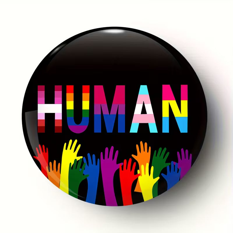 Human Pride Button mit buntem LGBTQIA+ Schriftzug und farbigen Händen auf schwarzem Hintergrund