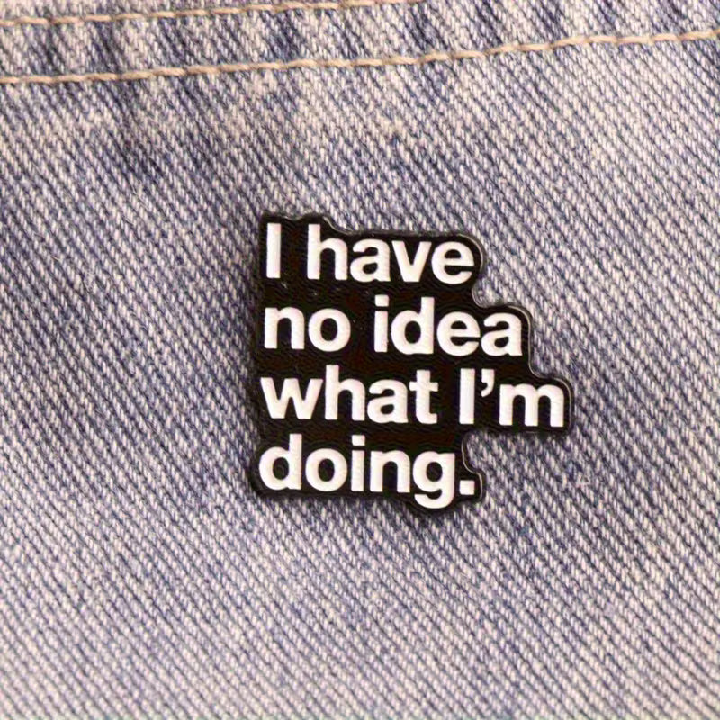 Schwarzer Statement-Pin mit weißem Text „I have no idea what I’m doing“ auf blauem Jeansstoff