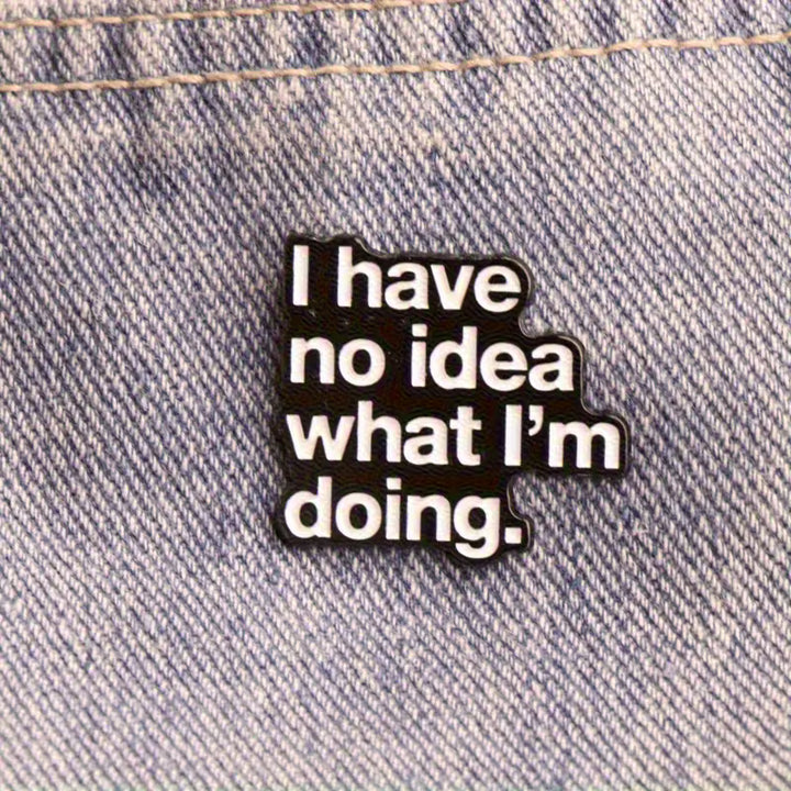 Schwarzer Statement-Pin mit weißem Text „I have no idea what I’m doing“ auf blauem Jeansstoff