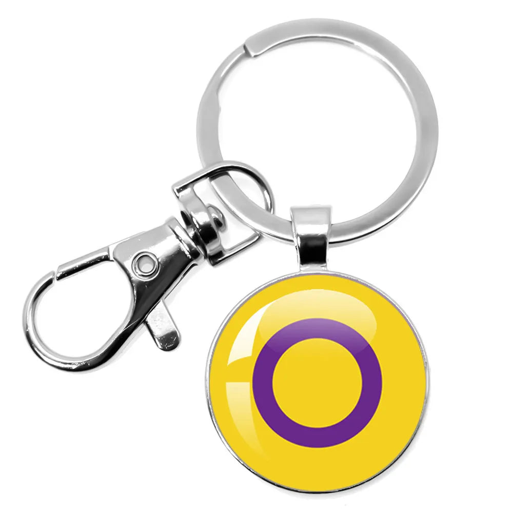 Runder Schlüsselanhänger aus Metall mit Intersex-Symbol in Gelb und Lila.