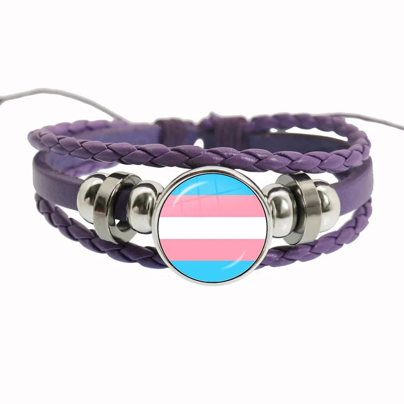 Ein Lederarmband mit geflochtenem Design und einem runden Anhänger in den Farben der Transflagge. Verziert mit silbernen Akzenten und perfekt als LGBTQ+-Pride-Schmuck.