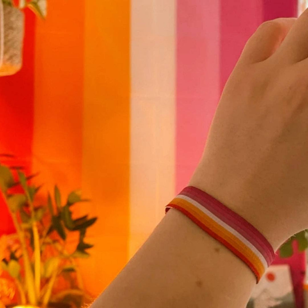 Lesben Pride Armband als gewebtes Festivalarmbändchen am Handgelenk getragen – Accessoire in den Farben der Lesben-Pride-Flagge für Pride, Festivals und den Alltag.