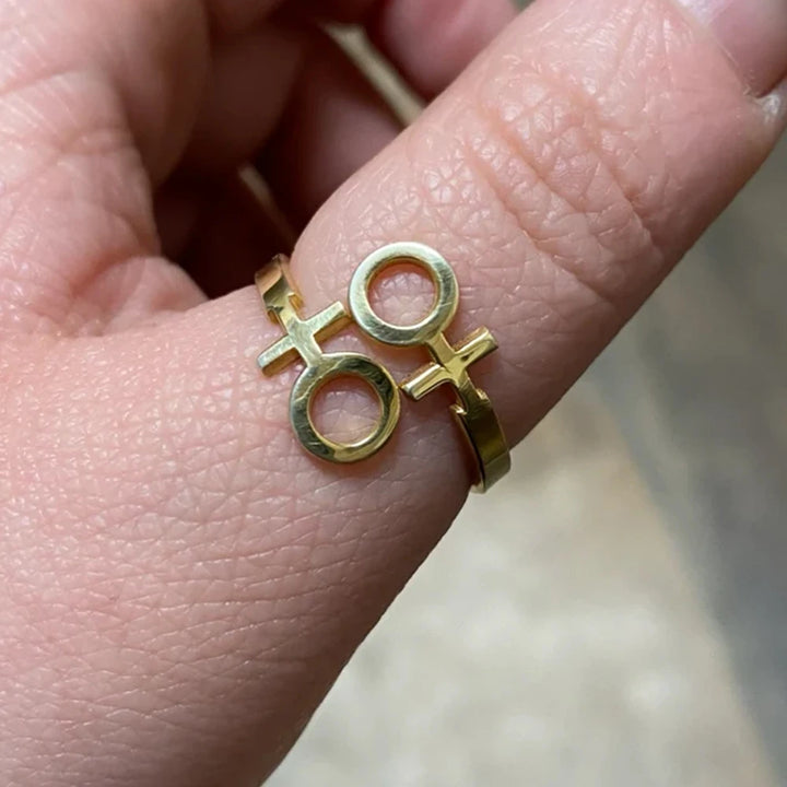 Verstellbarer lesbischer Ring mit Doppel-Venus-Symbol in Gold-Optik, getragen an einem Finger.