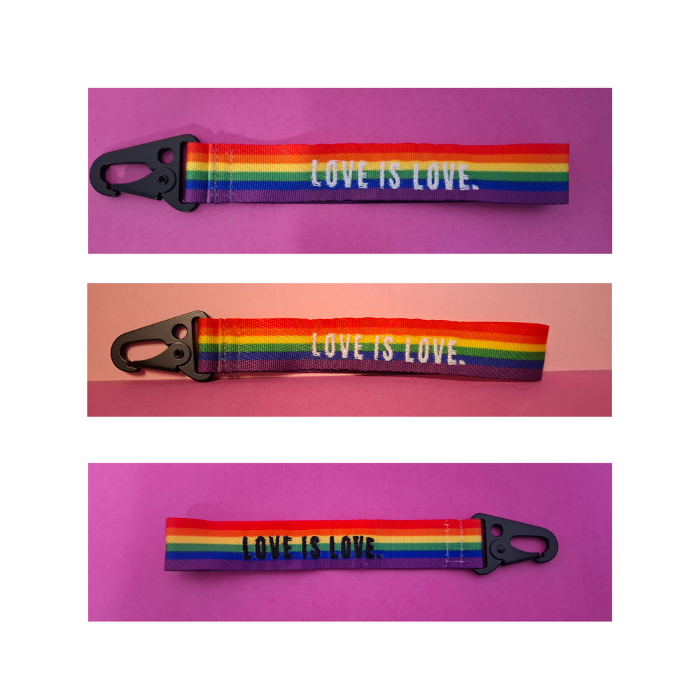 Regenbogen-Schlüsselanhänger mit schwarzem Karabiner und der Aufschrift „LOVE IS LOVE“. LGBTQIA+ Pride Accessoire aus robustem Gurtband in drei Ansichten auf farbigem Hintergrund.