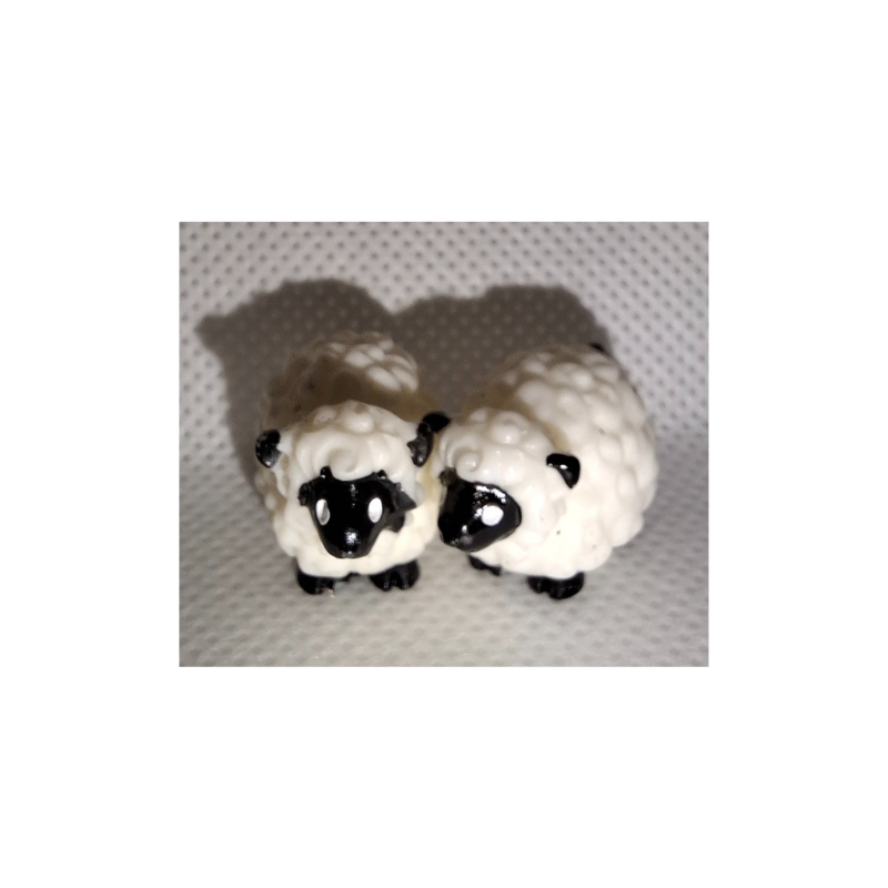 Zwei kleine realistische Mini-Schaf-Figuren aus Kunststoff auf heller Oberfläche