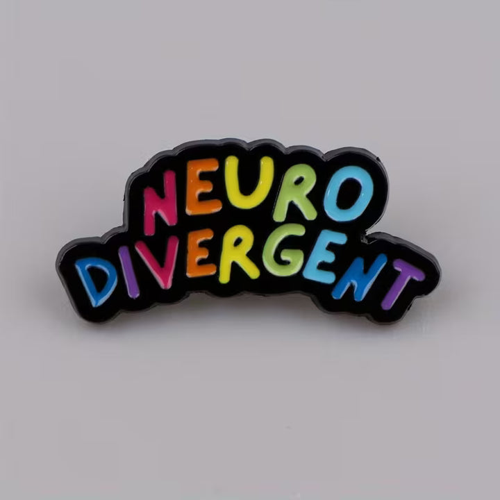 Neurodivergent Emaille-Pin mit buntem Regenbogen-Schriftzug auf neutralem grauen Hintergrund