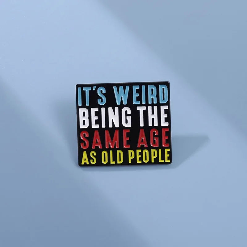 Rechteckiger Pin mit buntem Text It's Weird Being the Same Age as Old People auf schwarzem Hintergrund