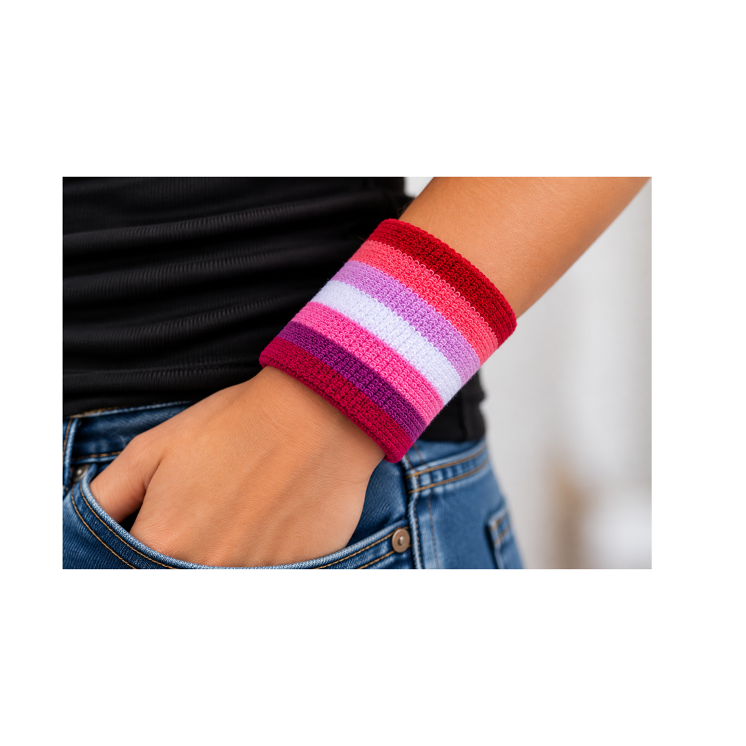 Pink Lesbian Pride Schweissband mit sieben Farbstreifen am Handgelenk getragen, kombiniert mit schwarzem Oberteil und Jeans
