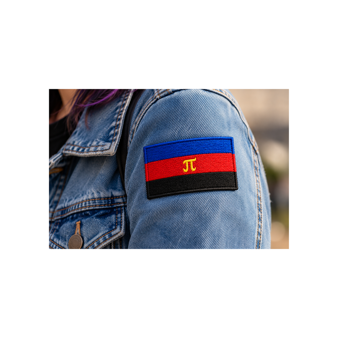 Gestickter Polyamorie Pride Patch mit Klettverschluss in Blau, Rot und Schwarz mit gelbem Pi-Symbol, 8 × 5 cm, getragen am Ärmel einer Jeansjacke.