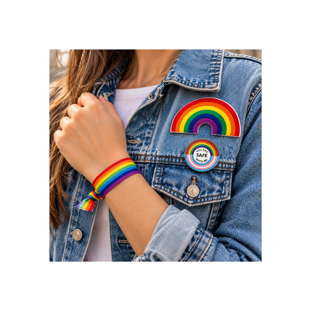Pride Regenbogen Set getragen an einer Person mit Jeansjacke: gestickter Regenbogen Patch und You Are Safe With Me Pin an der Jacke sowie Regenbogen Armband am Handgelenk.