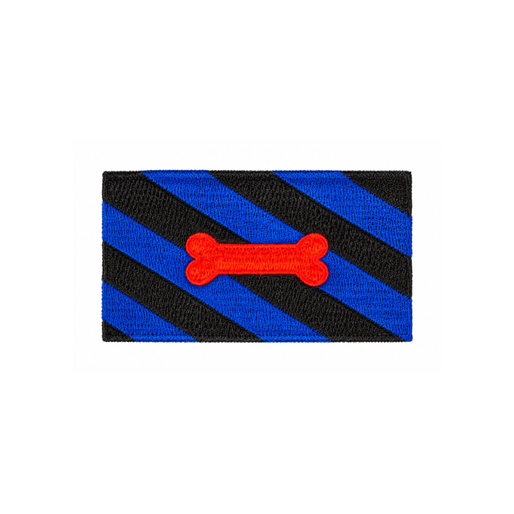 Gestickter Puppy Play Patch, 8 × 5 cm, mit diagonalen blau-schwarzen Streifen und rotem Knochenmotiv. Rechteckiger Aufnäher ohne Klettverschluss auf weissem Hintergrund.