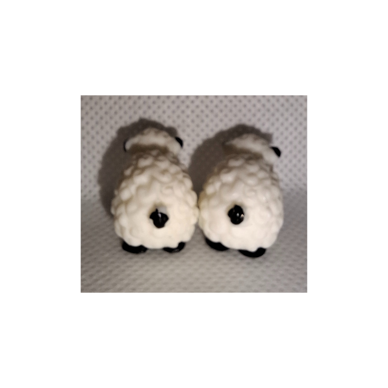 Zwei kleine realistische Mini-Schaf-Figuren aus Kunststoff auf heller Oberfläche