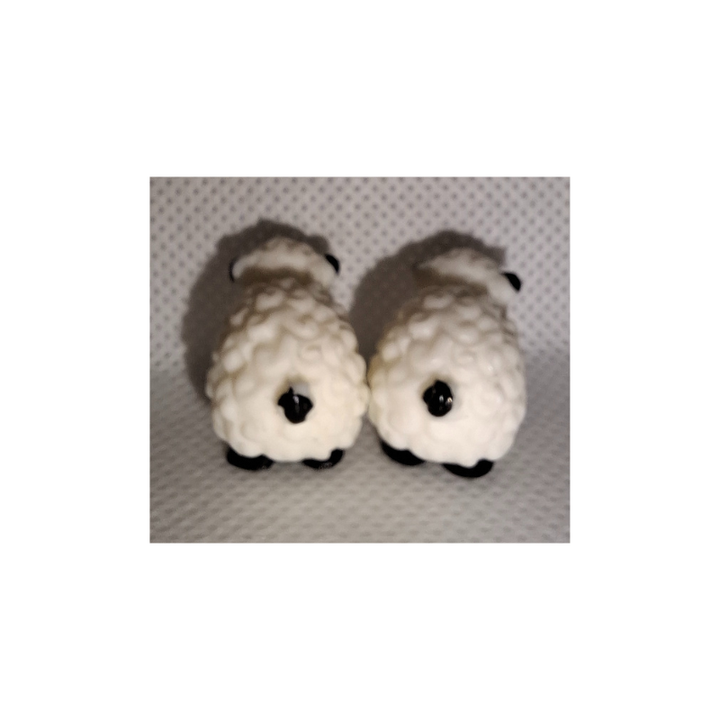 Zwei kleine realistische Mini-Schaf-Figuren aus Kunststoff auf heller Oberfläche