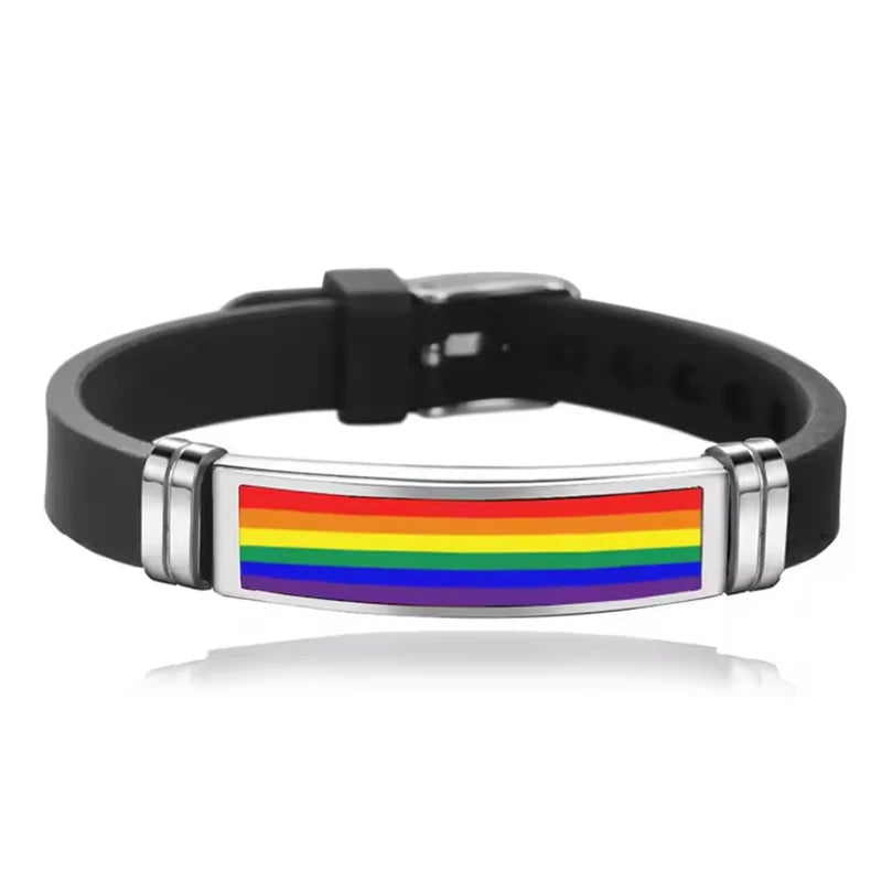 Ein schwarzes Silikonarmband mit einem rechteckigen Edelstahl-Element, das in den Farben der Regenbogenflagge gestaltet ist. Das Armband ist verstellbar und kombiniert modernes Design mit LGBTQ+-Pride.
