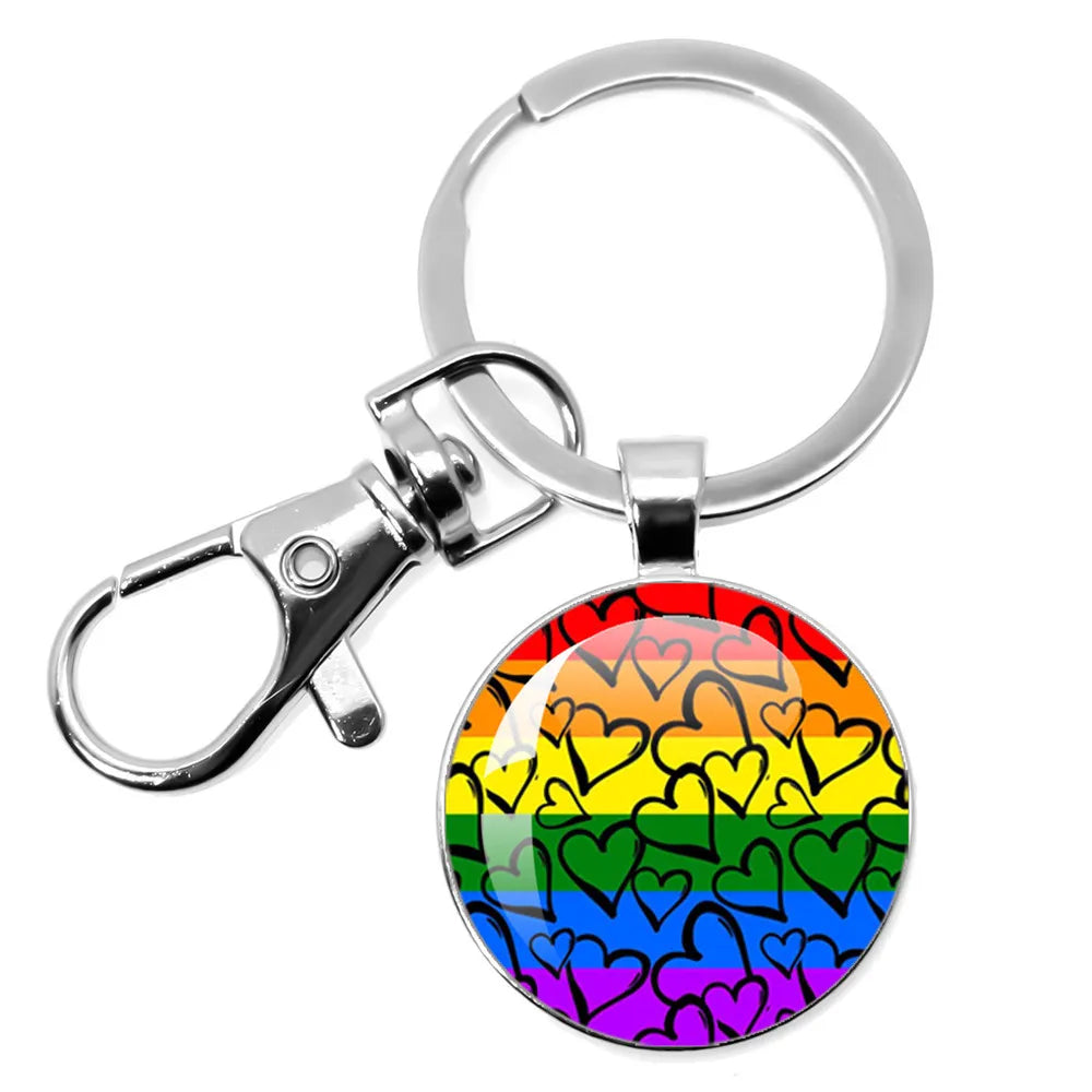 Runder Metall-Schlüsselanhänger mit Regenbogenstreifen und schwarzem Herzmuster.