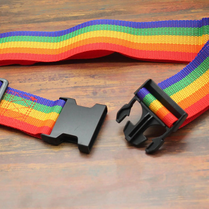 Nahaufnahme eines Regenbogen-Koffergurts mit robuster Schnalle, geöffnet auf einem Holztisch.