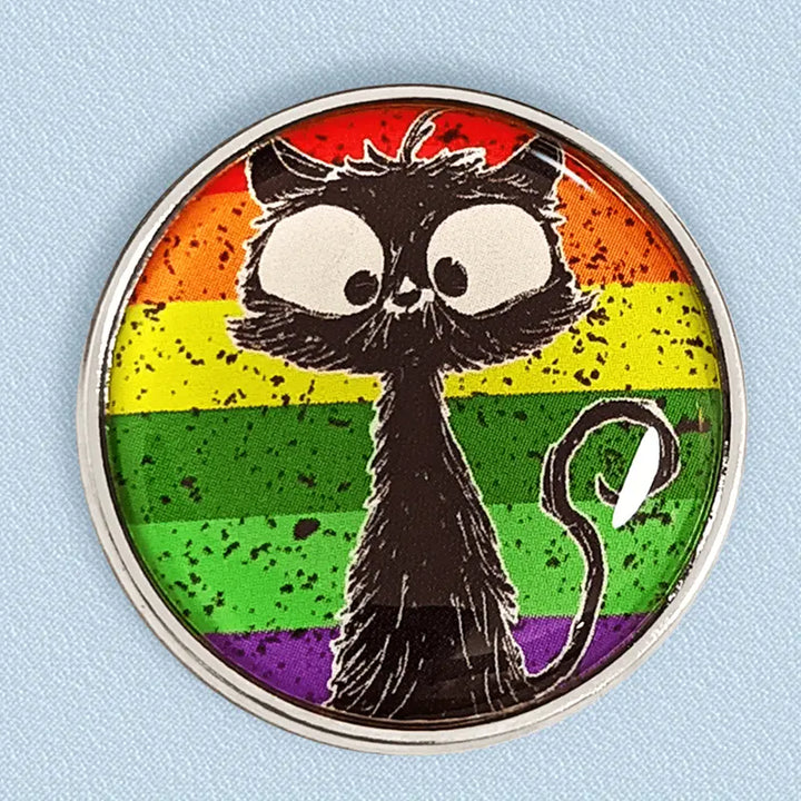Runder Emaille-Anstecker mit bunter Regenbogenflagge im Hintergrund und einer schwarz gezeichneten, großäugigen Katze im Vordergrund.