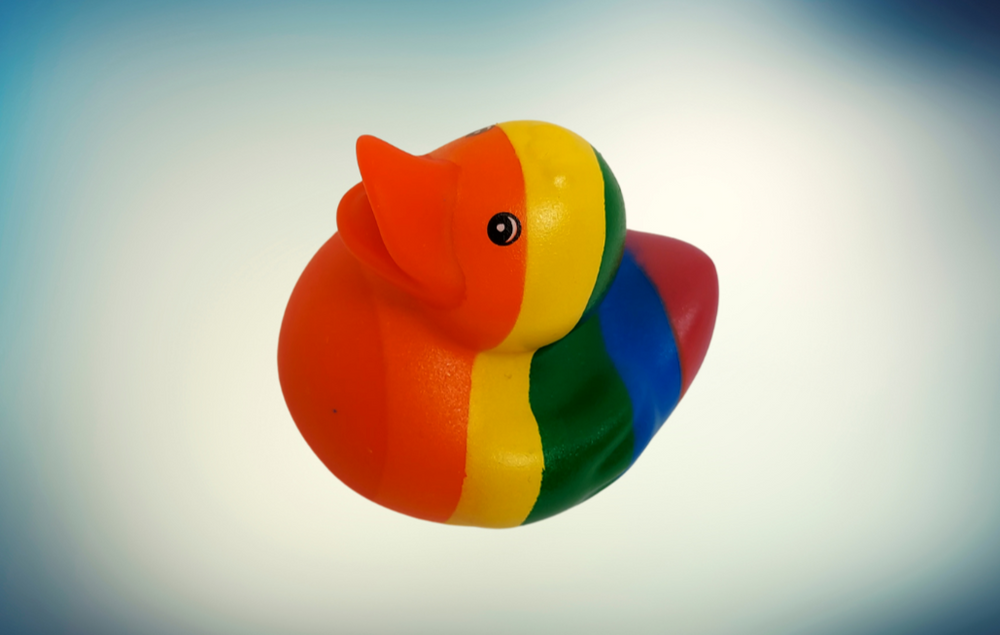  Bunte Quietscheentchen mit Regenbogenmuster auf einem blauen Hintergrund.