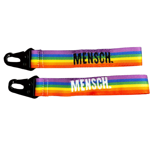 Regenbogen Schlüsselanhänger mit der Aufschrift „Mensch.“ – handgemacht in der Schweiz, bestickt auf farbigem Regenbogenband mit schwarzem Karabiner.