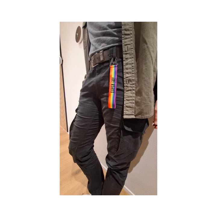 Regenbogen Schluesselanhaenger mit Aufdruck Super Gay am Hosenbund einer Cargo Hose