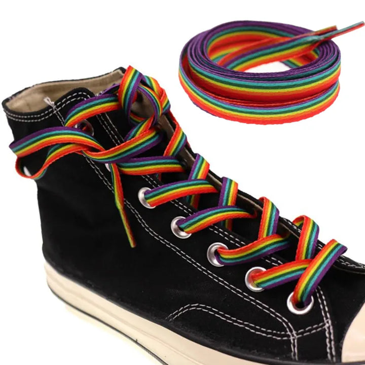 Bunter Sneaker mit Regenbogen-Schnürsenkeln, die farbenfrohe Akzente setzen. Eine zusätzliche Rolle der regenbogenfarbenen Schnürsenkel ist oben rechts im Bild zu sehen.