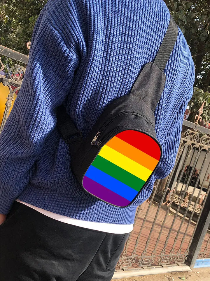Person trägt eine schwarze Sling-Tasche mit Regenbogen-Frontdesign als Pride-Umhängetasche