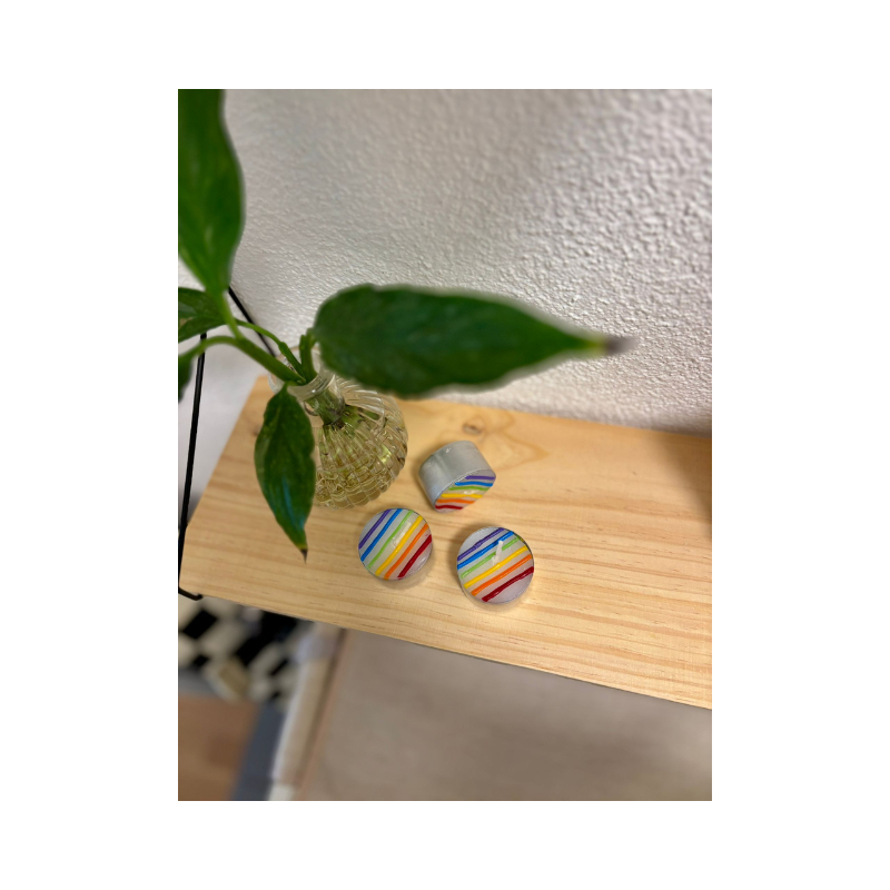 Drei handgemachte Regenbogen Teelichter als LGBTQIA Pride Kerzen auf Holzoberfläche in einem Safe Space