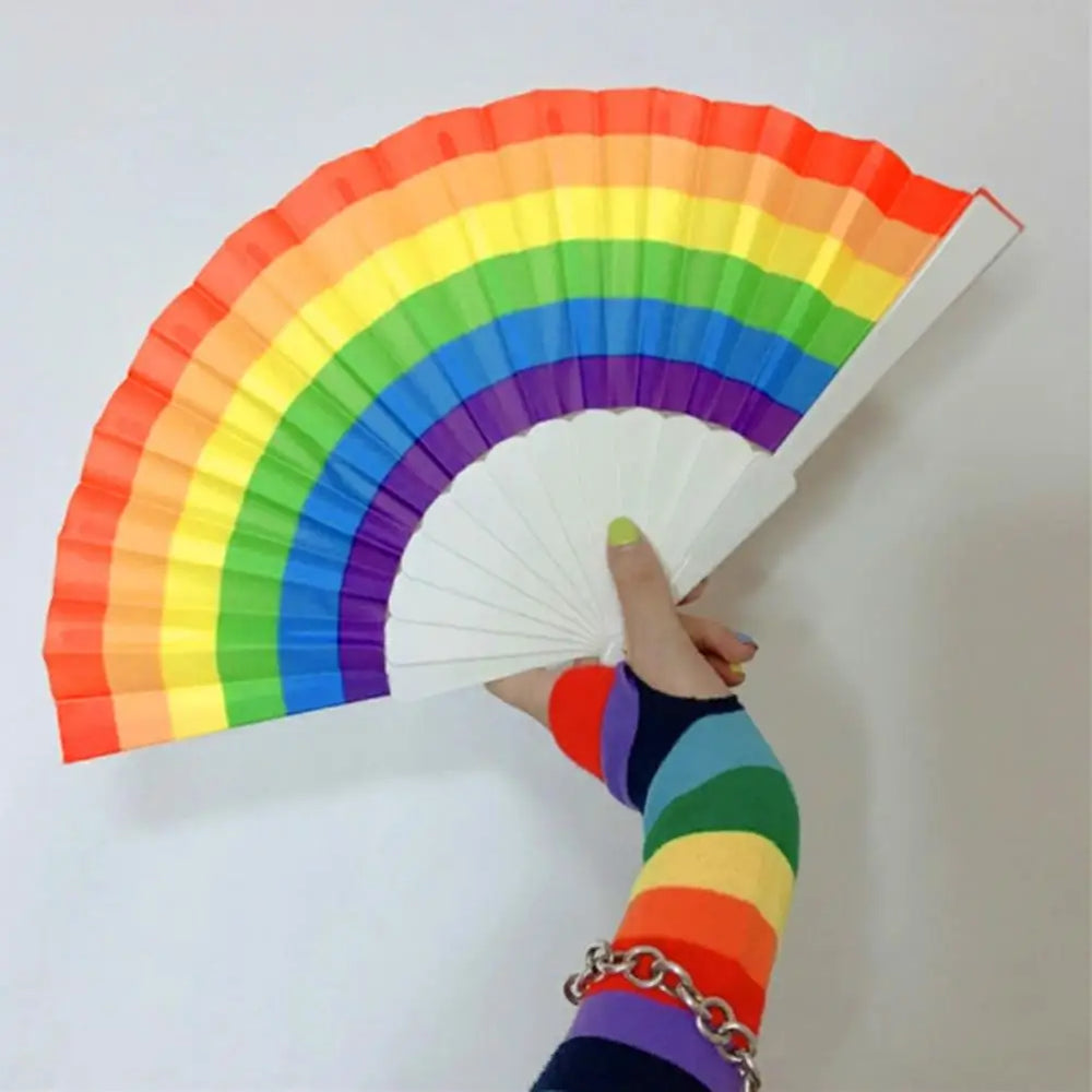 Handfächer in Regenbogenfarben, gehalten von einer Hand mit regenbogenfarbenem Handschuh.