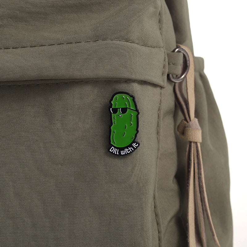 Ein witziger Ansteck-Pin in Form einer coolen Gurke mit Sonnenbrille und dem Wortspiel „Dill with it“. Perfekt für Fans von humorvollen Wortspielen, Meme-Kultur und lustigen Accessoires.