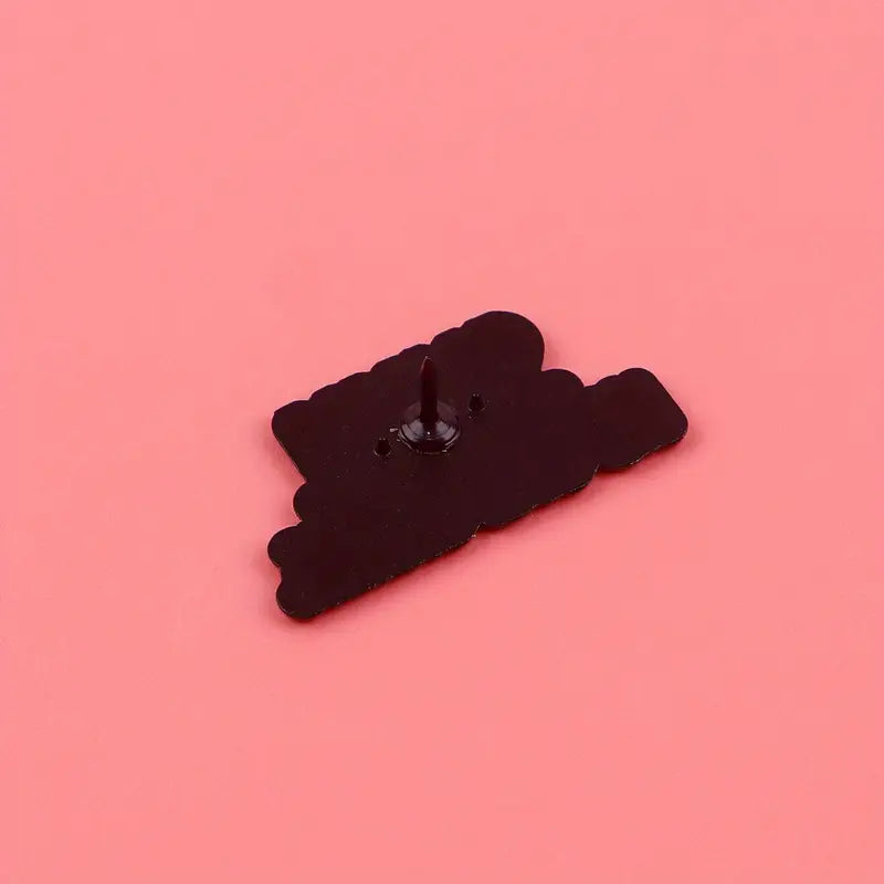 Rückseite eines schwarzen Pins mit Nadel auf rosa Hintergrund, Design Shhh No One Cares