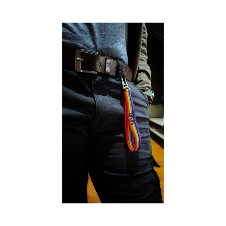 Regenbogen Schluesselanhaenger am Hosenbund befestigt, getragen an dunkler Hose mit Guertel.