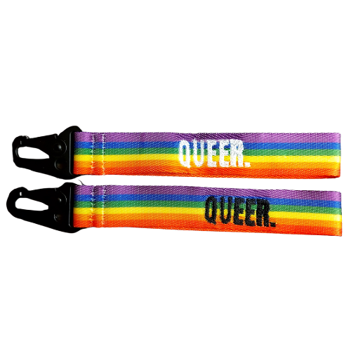 Queere Schlüsselanhänger im Regenbogen Desigen. Mit schwarzer und weisser Schrift.