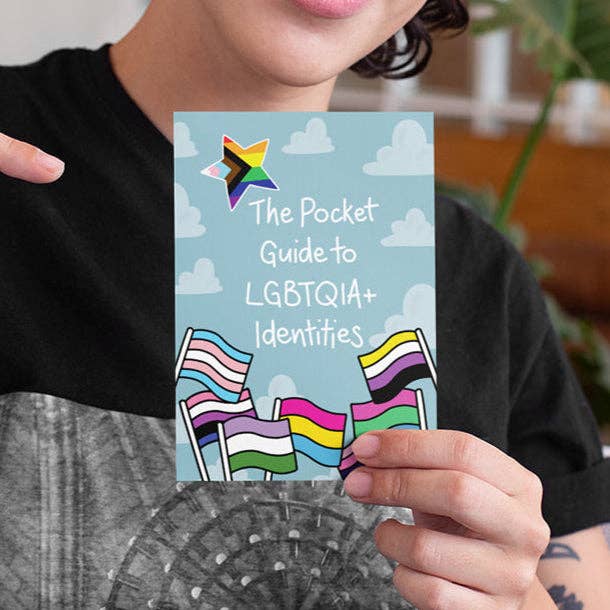 Person hält den Pocket Guide to LGBTQIA+ Identities mit über 40 Pride-Flaggen und Erklärungen zu queeren Identitäten im A6-Format.