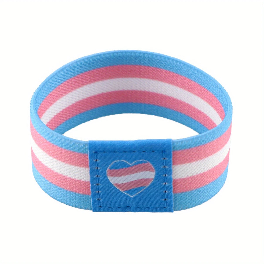 Elastisches Armband in den Farben der Transgender-Flagge (hellblau, rosa, weiß) mit Herzsymbol – getragen am Handgelenk.
