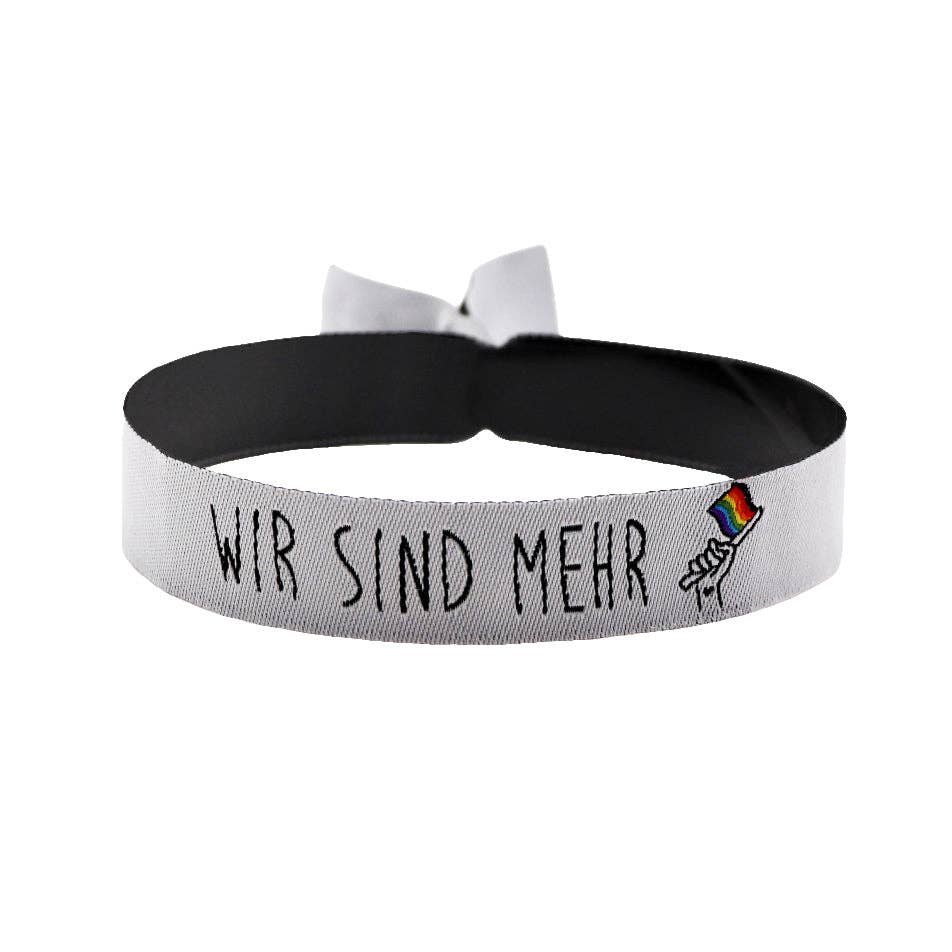 Gewebtes "Wir sind mehr" Armband mit Progress-Pride-Flagge und Metallverschluss als Festivalarmband für Vielfalt, Zusammenhalt und Pride.